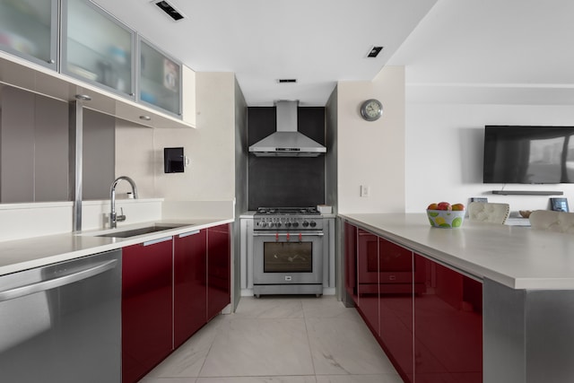 21 S End Ave Unit 321/421, New York City, NY 10280 - kitchen featuring wall chimney range hood, stainless steel appliances, light marble finish floors, a peninsula, and red cabinets