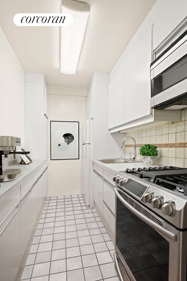 145 E 15th St Unit 8R, New York City, NY 10003 - kitchen featuring stainless steel range with gas cooktop, freestanding refrigerator, white cabinets, light countertops, and backsplash