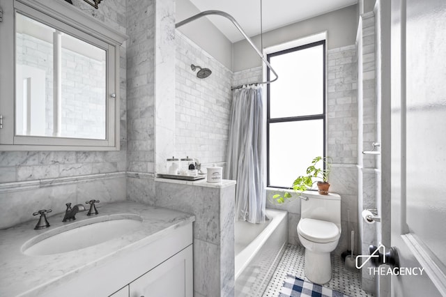full bathroom featuring tile walls, healthy amount of natural light, toilet, shower / bath combination with curtain, and vanity