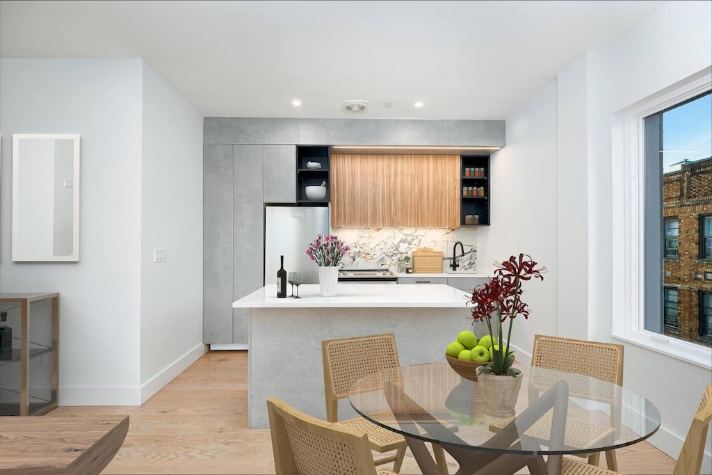 kitchen with refrigerator, tasteful backsplash, sink, light hardwood / wood-style floors, and kitchen peninsula