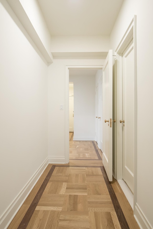 corridor featuring parquet floors and baseboards