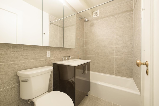 full bath featuring toilet, tile walls, vanity, and shower / washtub combination