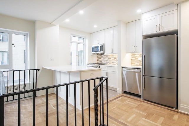 kitchen with light parquet floors, stainless steel appliances, decorative backsplash, and white cabinets