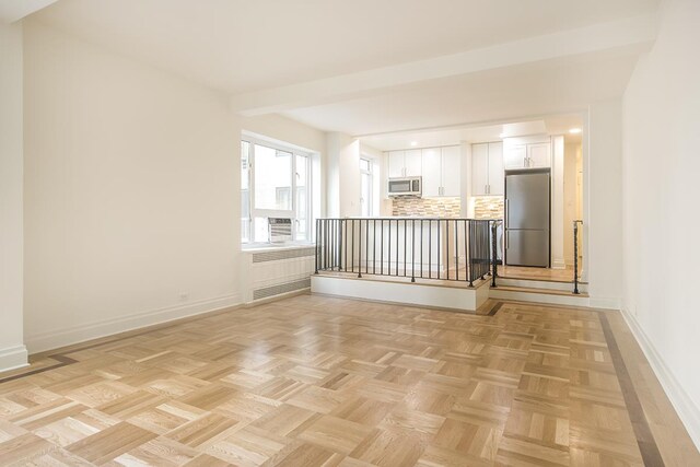 spare room featuring baseboards and radiator