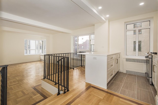 kitchen with recessed lighting, light countertops, white cabinets, gas range, and radiator
