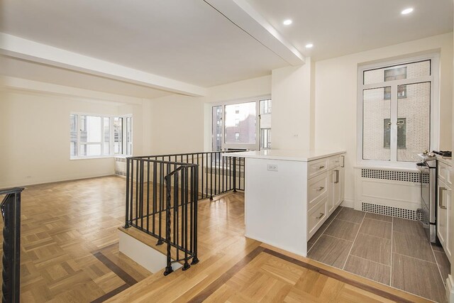 20 E 35th St Unit 8-K, New York City, NY 10016 - kitchen with radiator, light countertops, recessed lighting, white cabinetry, and a peninsula