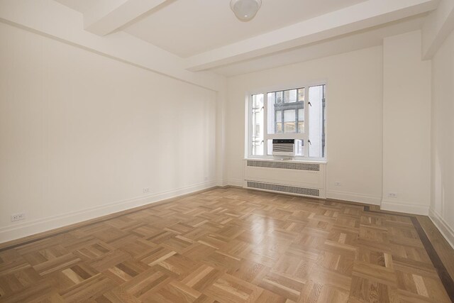 spare room featuring radiator, beamed ceiling, and baseboards