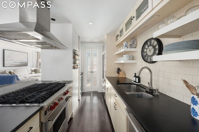 kitchen with island range hood, stainless steel stove, tasteful backsplash, sink, and dark wood-type flooring