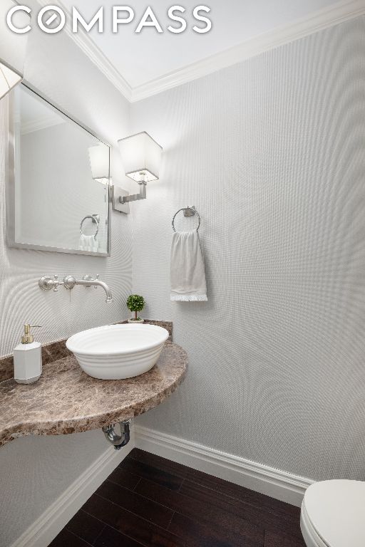 bathroom with ornamental molding, toilet, and sink