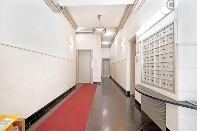 corridor featuring elevator, a high ceiling, and a mail area