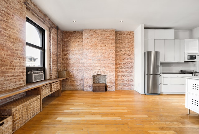 interior space featuring brick wall, cooling unit, and light hardwood / wood-style floors