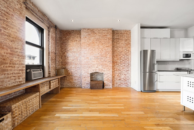 kitchen featuring cooling unit, white microwave, freestanding refrigerator, and brick wall