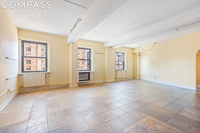 unfurnished room featuring radiator, a wealth of natural light, a textured ceiling, and track lighting