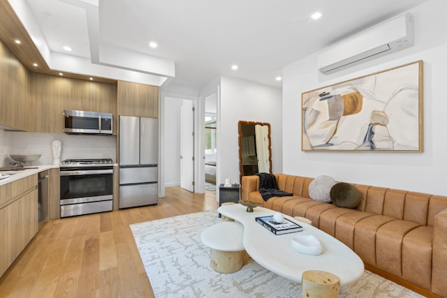 living room with a wall mounted AC and light hardwood / wood-style flooring