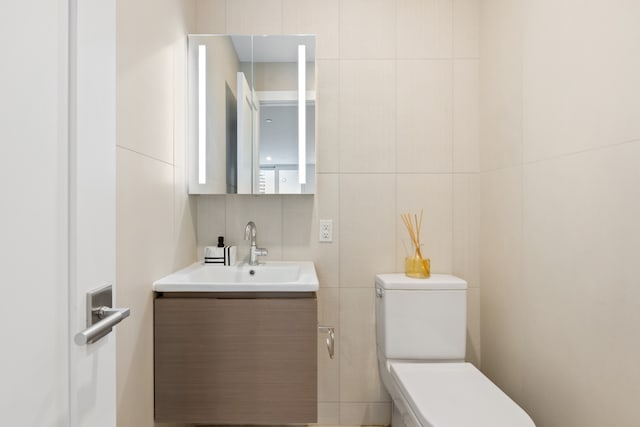 bathroom featuring tile walls, vanity, and toilet