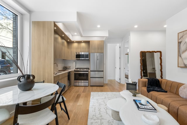 kitchen with brown cabinetry, modern cabinets, stainless steel appliances, light countertops, and light wood-style floors