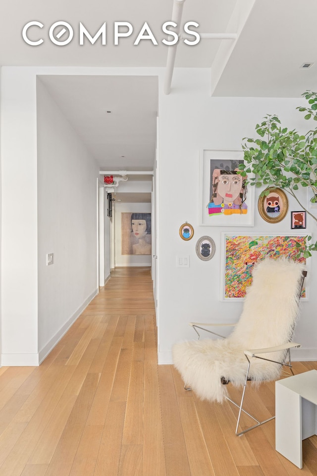 corridor featuring baseboards and light wood-style flooring