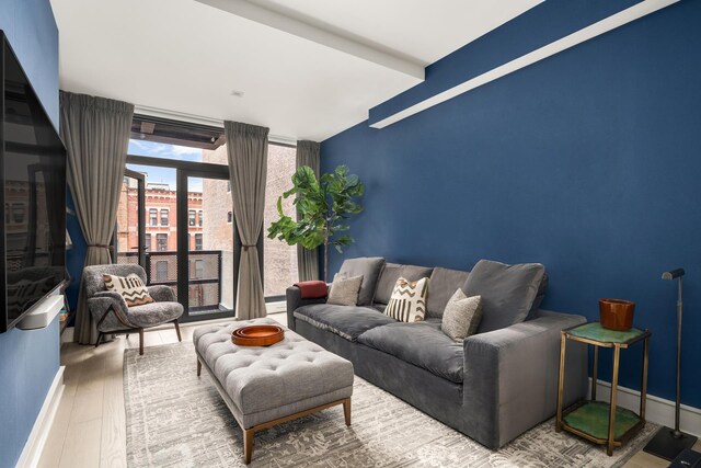 living area with a wall of windows, wood finished floors, and baseboards