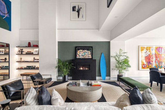 living area featuring a lit fireplace and baseboards