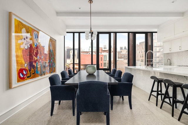 dining room with light wood-style floors, baseboards, a city view, and beamed ceiling