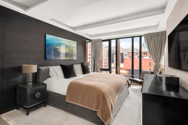 bedroom with access to exterior, wooden walls, and a raised ceiling