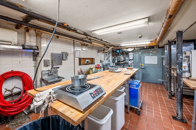 kitchen featuring a wall mounted AC, butcher block counters, and dark tile patterned flooring