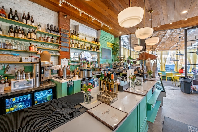 interior space featuring hanging light fixtures, rail lighting, wood ceiling, and a community bar