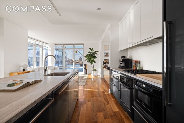 kitchen featuring extractor fan, sink, white cabinets, stainless steel appliances, and dark wood-type flooring