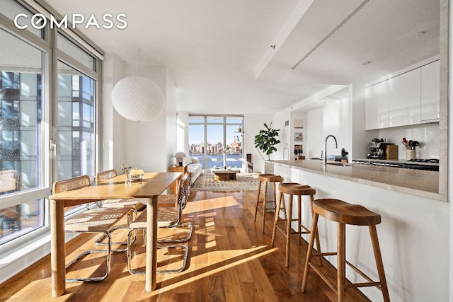 dining room with white cabinetry, sink, a breakfast bar area, and light wood-type flooring