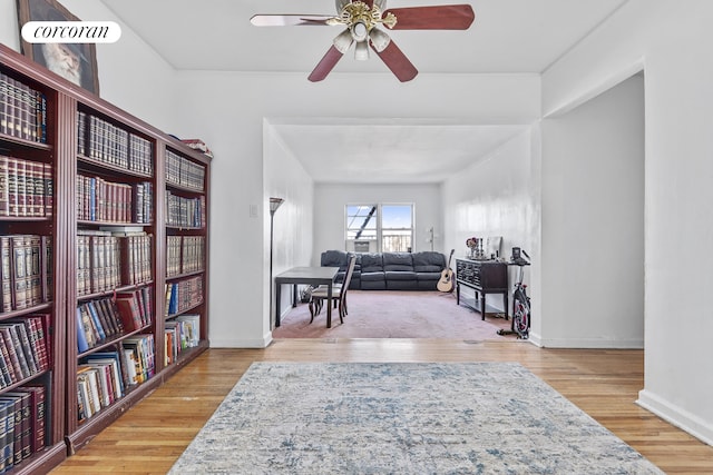 living area featuring wood finished floors, a ceiling fan, and baseboards