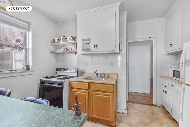 kitchen with tasteful backsplash, white cabinetry, sink, and white appliances