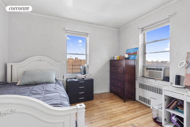 bedroom with cooling unit, radiator, light hardwood / wood-style flooring, and ornamental molding