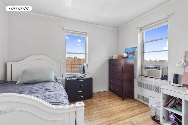 bedroom with light wood-style flooring, cooling unit, ornamental molding, and radiator