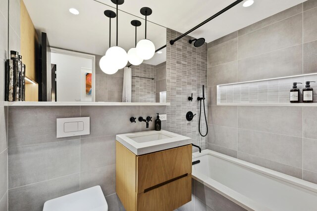 full bathroom featuring tile walls, vanity, toilet, and tiled shower / bath