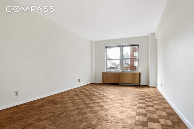 empty room with radiator heating unit and baseboards