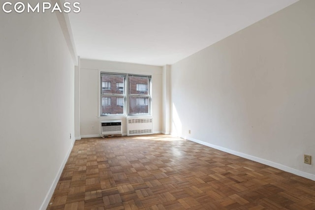 unfurnished room featuring heating unit, radiator, and dark parquet floors