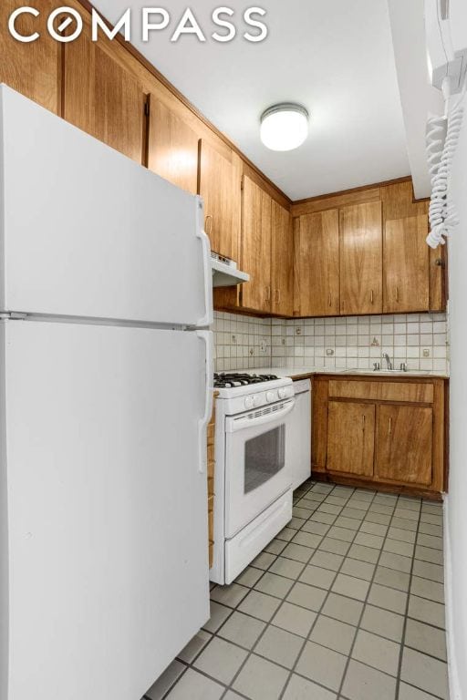 kitchen featuring tasteful backsplash, light tile patterned flooring, sink, and white appliances