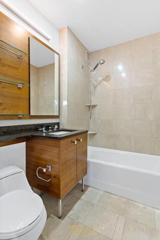 full bathroom featuring tiled shower / bath combo, vanity, and toilet