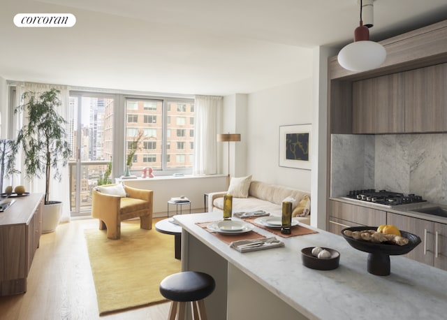 interior space with backsplash, light hardwood / wood-style floors, and stainless steel gas stovetop