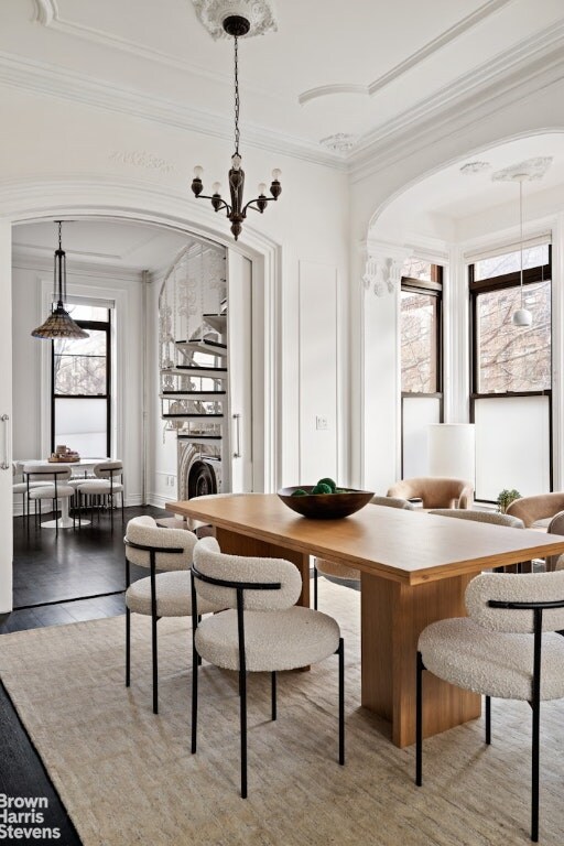 unfurnished dining area with crown molding, hardwood / wood-style flooring, washer / dryer, and a chandelier