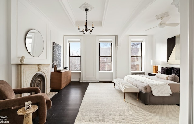 bedroom with a raised ceiling, ceiling fan with notable chandelier, and dark hardwood / wood-style flooring