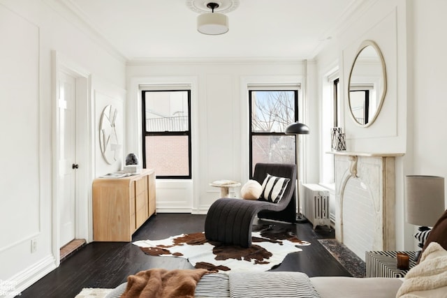 sitting room with dark wood-type flooring, radiator heating unit, and crown molding