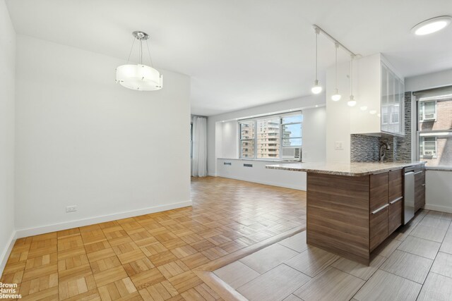 kitchen featuring tasteful backsplash, dishwasher, pendant lighting, and kitchen peninsula