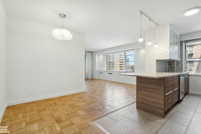 kitchen with decorative backsplash, light parquet flooring, dishwasher, and kitchen peninsula