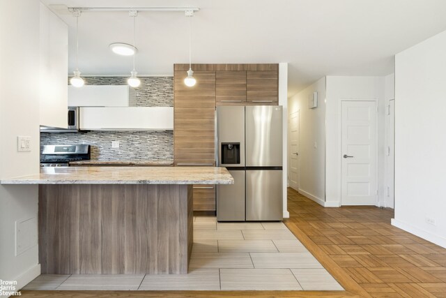 kitchen with a breakfast bar area, appliances with stainless steel finishes, backsplash, decorative light fixtures, and kitchen peninsula