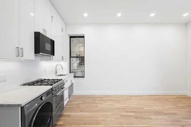 244 Riverside Dr Unit 2G, New York City, NY 10025 - kitchen with black microwave, a sink, light wood-style flooring, washer / clothes dryer, and baseboards