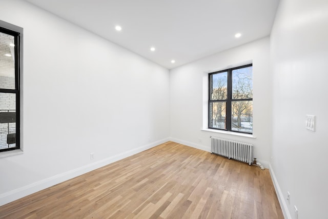 empty room featuring recessed lighting, baseboards, light wood finished floors, and radiator heating unit