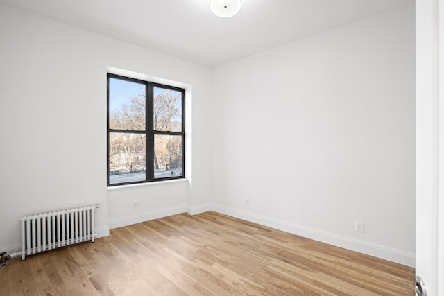 unfurnished room featuring light wood finished floors, radiator heating unit, and baseboards