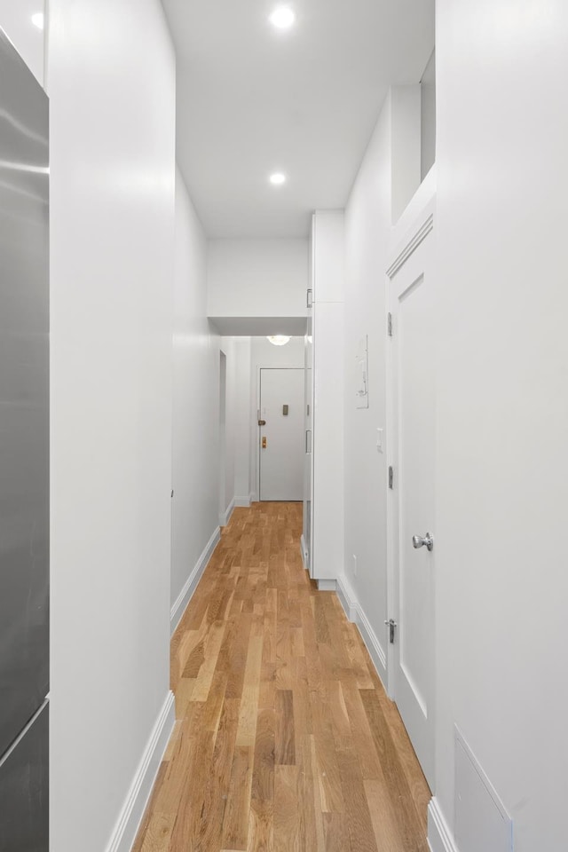 corridor with light wood-style flooring, baseboards, and recessed lighting