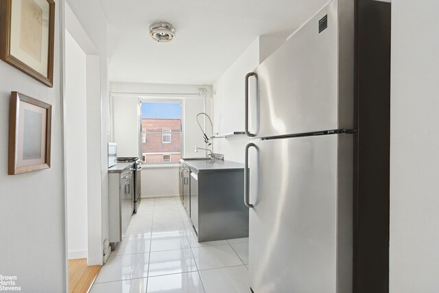 kitchen featuring stainless steel appliances, sink, and light tile patterned floors